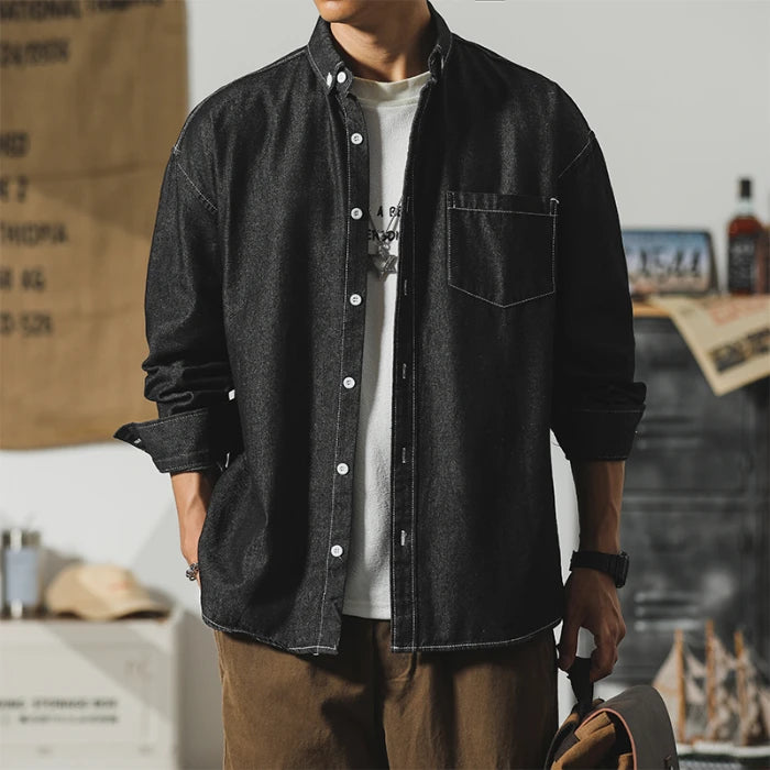 Men's black denim jacket with a minimalist design, featuring a pocket and button closure, perfect for layering.