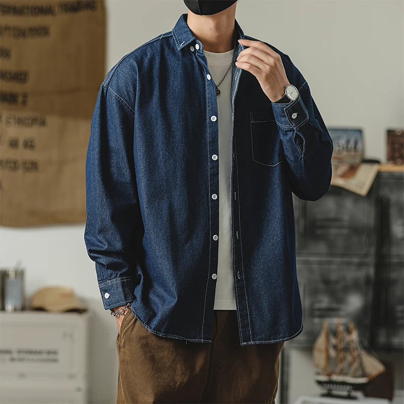 Stylish man wearing a dark denim jacket with a white shirt and brown pants, showcasing casual fashion.