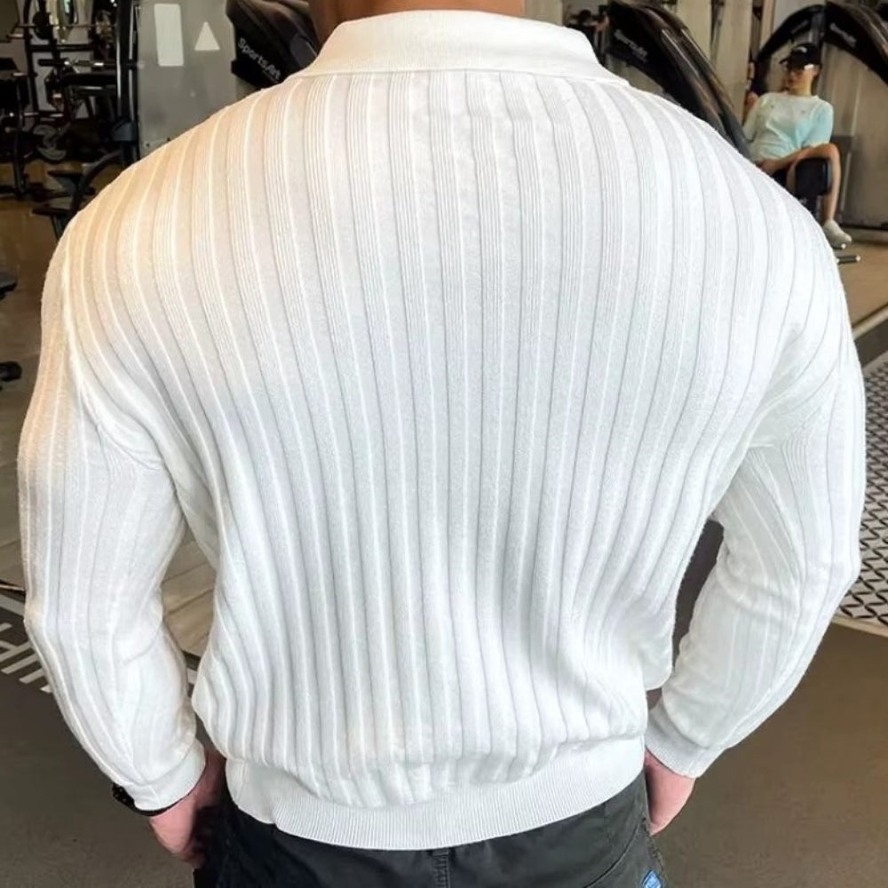 Back view of a muscular man wearing a white ribbed zip polo shirt in a gym setting.