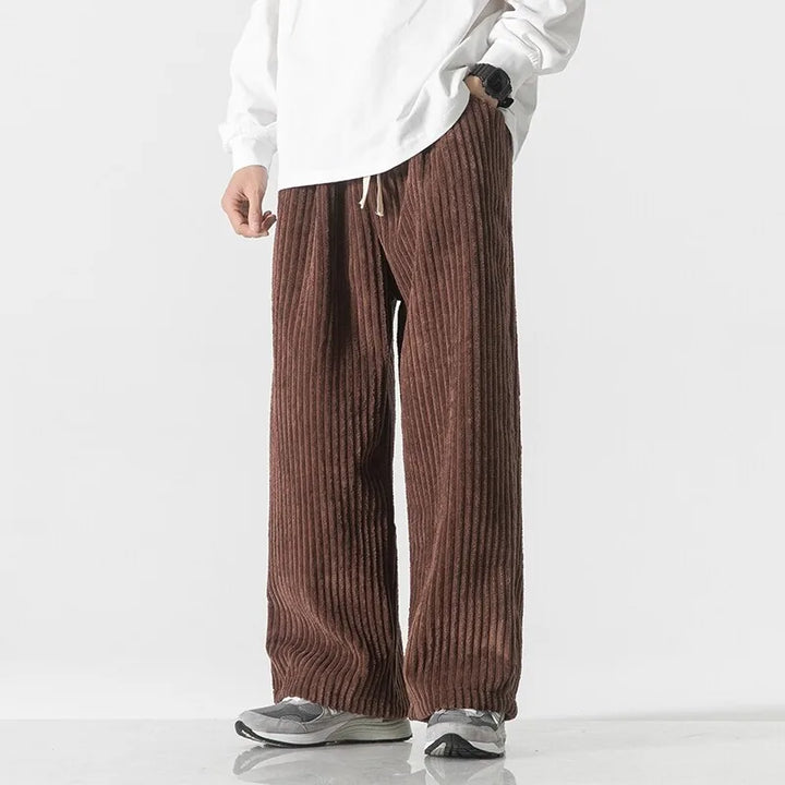 Brown corduroy pants with wide-leg fit, elastic waistband, and adjustable drawstring, styled with a loose white top.