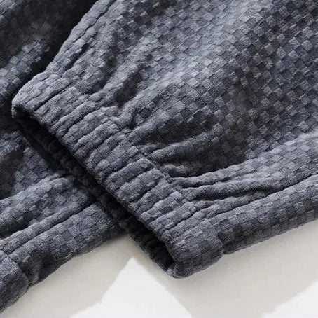 Close-up of Riden checkered corduroy pants showcasing the textured fabric and tapered fit cuffs.