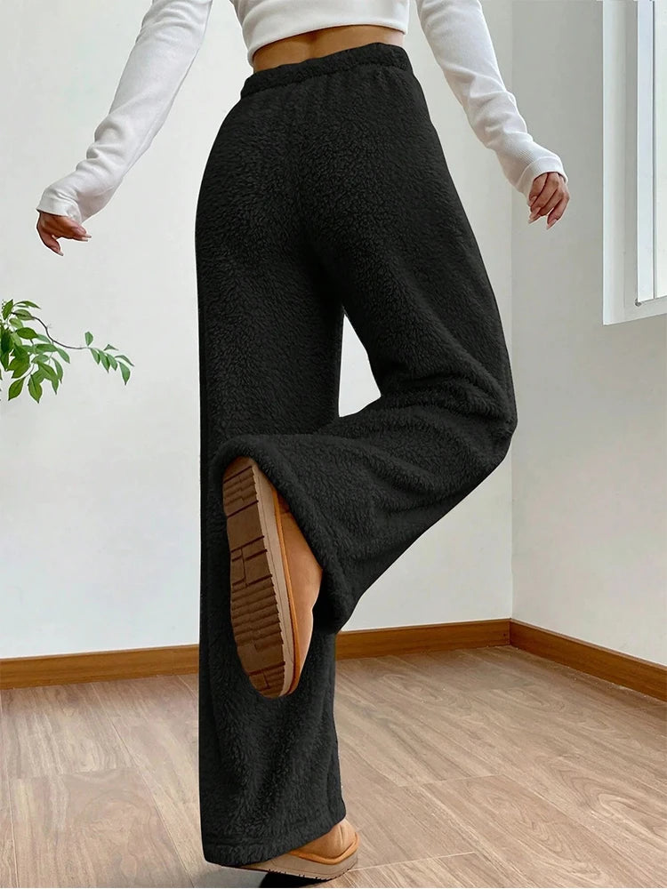 Woman wearing fluffy black sherpa flow sweatpants with wide-leg fit, showing relaxed silhouette and drawstring waist.