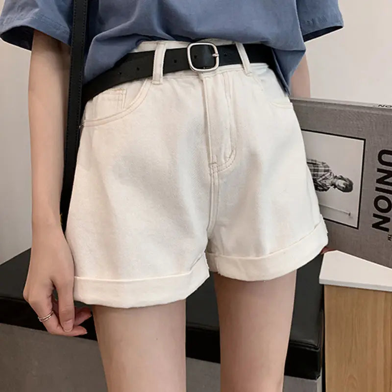 High-waisted Sienna Retro denim shorts in white with rolled hems, paired with a black belt and casual top.