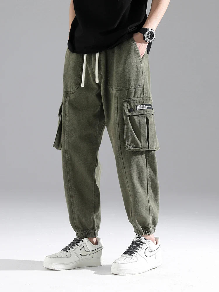 Lennox cargo joggers in heavyweight cotton blend with oversized snap pockets and elastic ankle cuffs, styled with casual sneakers.