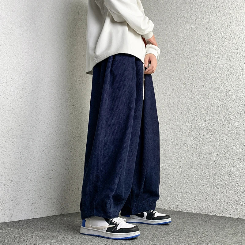 Model wearing Arlo Corduroy Pants in navy blue, showcasing wide-leg fit and relaxed style with sneakers.