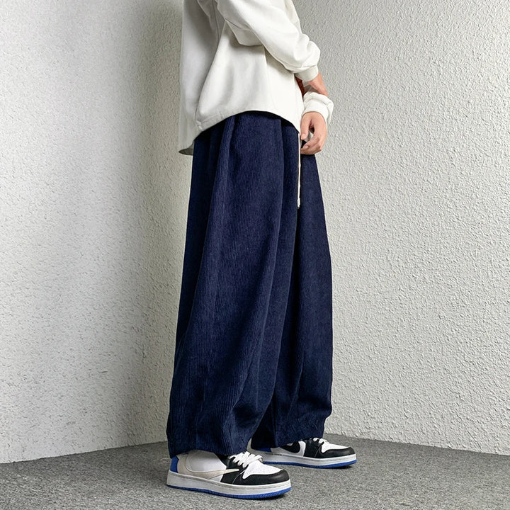 Model wearing Arlo Corduroy Pants in navy blue, showcasing wide-leg fit and relaxed style with sneakers.
