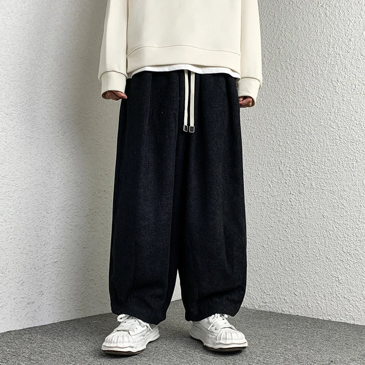 Model wearing Arlo Corduroy Pants in black with a wide-leg fit and adjustable drawstring waist, paired with white sneakers.