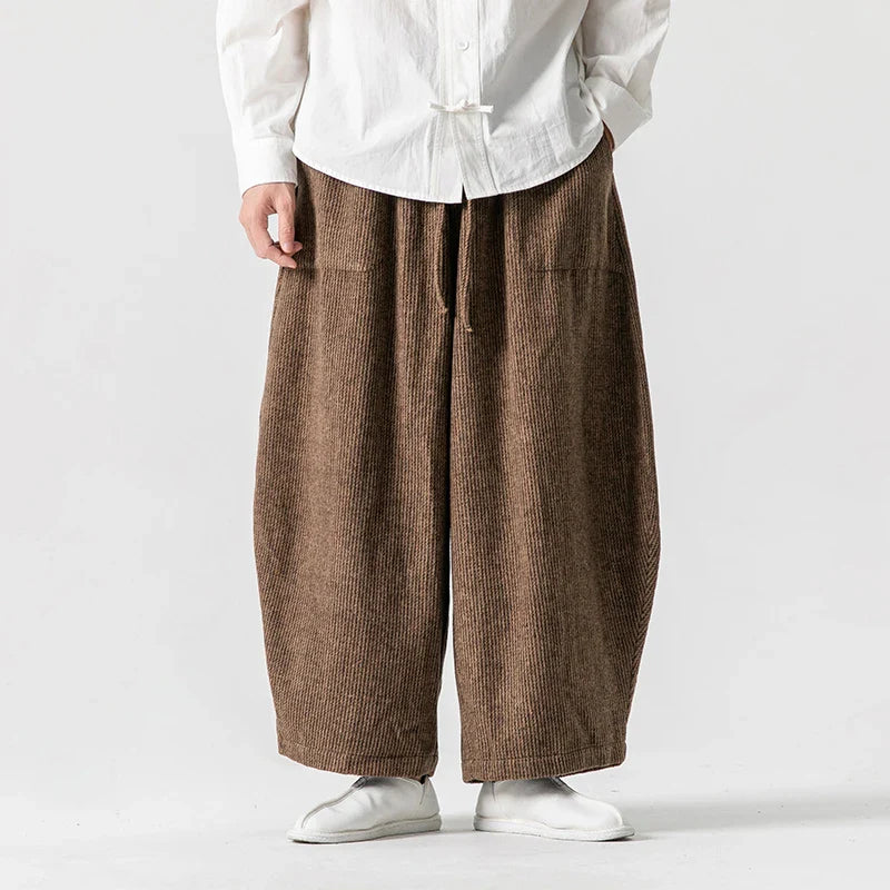 Henderson wide-leg corduroy pants in brown, featuring deep pleats and gathered elastic waistband for comfort.