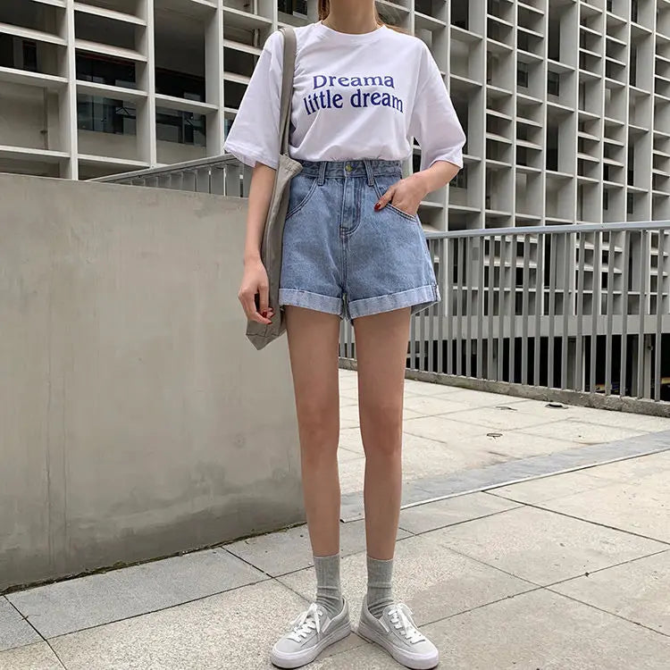 Model wearing high-waisted Sienna Retro Denim Shorts with a white graphic tee and sneakers, showcasing a casual Y2K style.