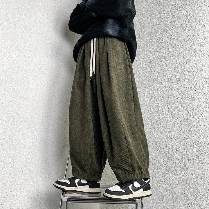 Arlo corduroy pants in olive green with adjustable waist and wide-leg fit, styled with a black hoodie and sneakers.