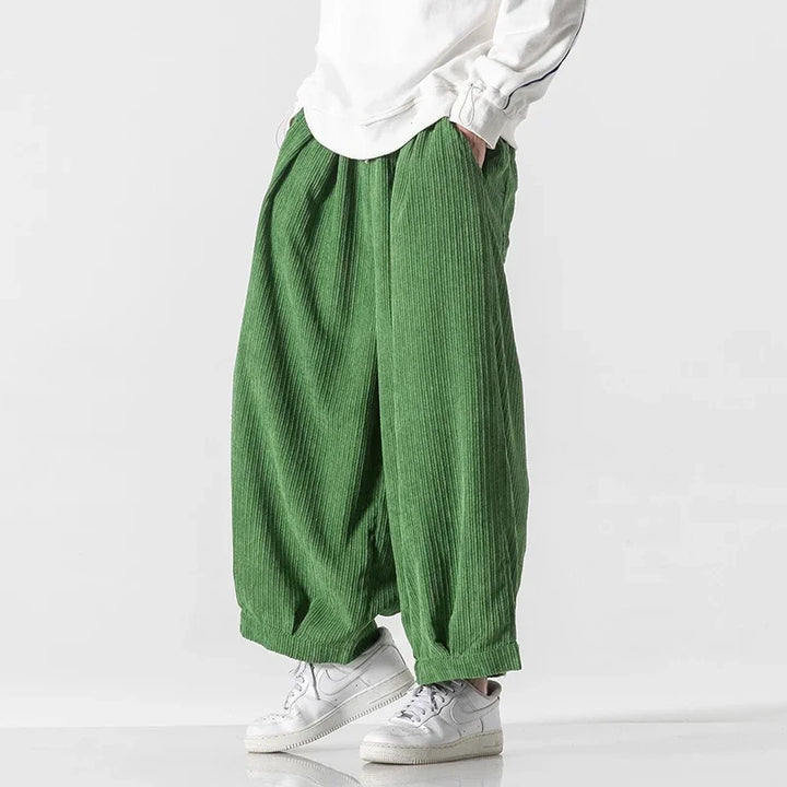 Oversized green corduroy pants with deep pleats, elastic waistband, and wide-leg silhouette for effortless comfort.