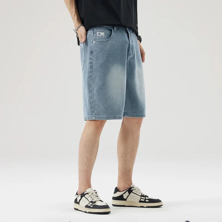 Men's Axel Faded Wash Denim Shorts featuring a relaxed straight-leg fit and unique crosshatch pattern, styled with sneakers.