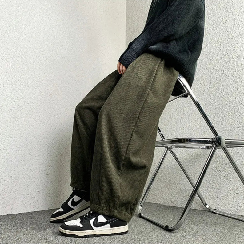 Model wearing Arlo corduroy pants in olive, featuring wide-leg fit and relaxed style, paired with sneakers.