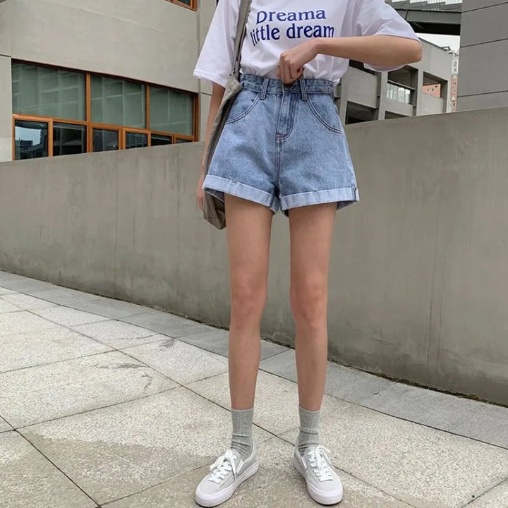 Model wearing high-waisted Sienna Retro Denim Shorts with cuffed hems and casual tee on urban street.