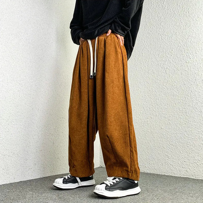 Arlo Corduroy Pants in brown with wide-leg fit, adjustable drawstring waist, and deep pockets, styled with sneakers.