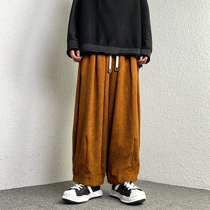 Person wearing Arlo corduroy pants with wide-leg fit, adjustable drawstring waist, and deep pockets, styled with sneakers.
