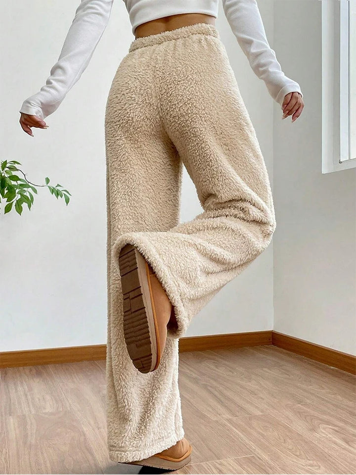 Woman wearing Sherpa Flow Sweatpants in beige, showcasing the fluffy texture and wide-leg silhouette.