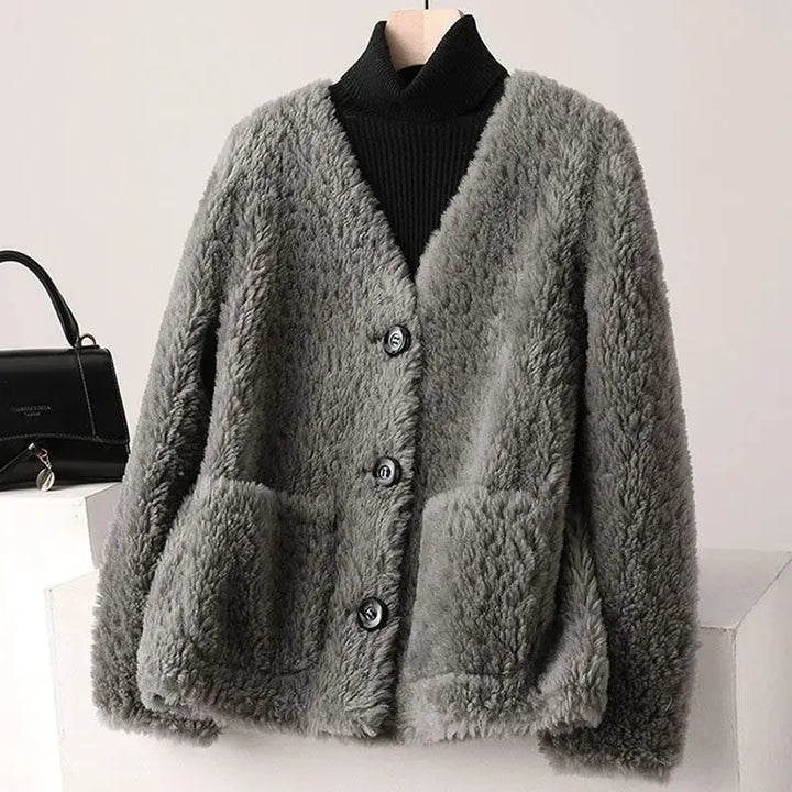 Gray fluffy cardigan on a mannequin with a black handbag in the background