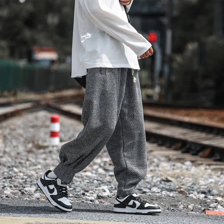 Person wearing Oslo Textured Joggers with black and white sneakers, walking along a railway track.