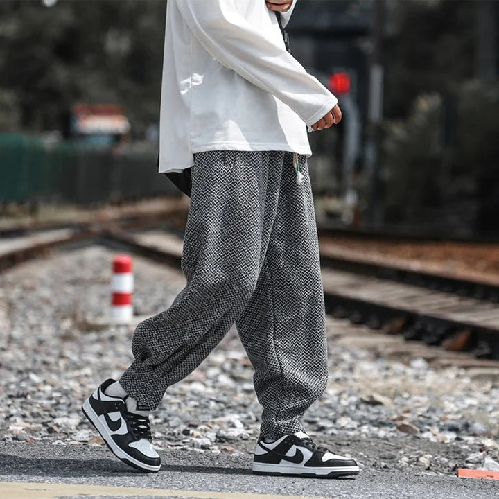 Person wearing Oslo Textured Joggers with black and white sneakers, walking along a railway track.