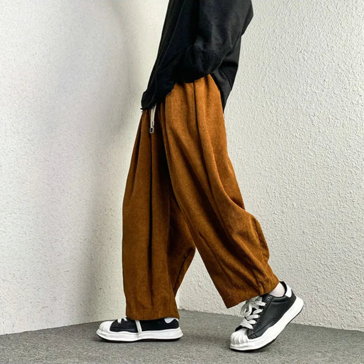 Model wearing Arlo corduroy pants in orange, showcasing wide-leg fit and adjustable drawstring waist.