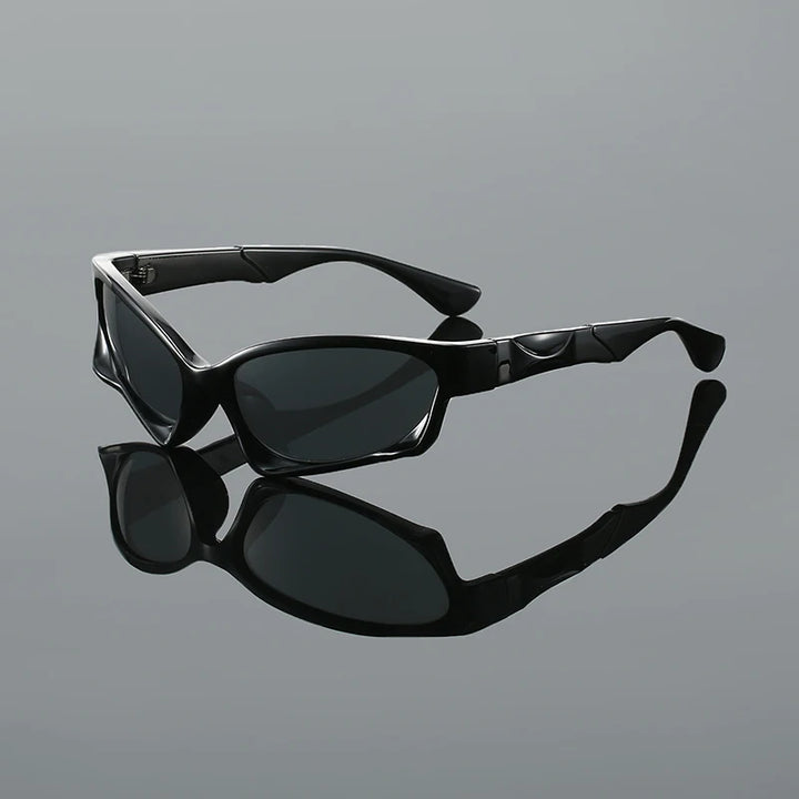 Astro Sunglasses with black alien-inspired angular frame and dark UV-protective lenses on a reflective surface.