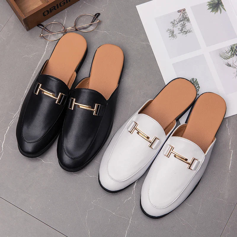 Santino backless slide loafers in black and white with gold bit hardware on a stylish gray background.