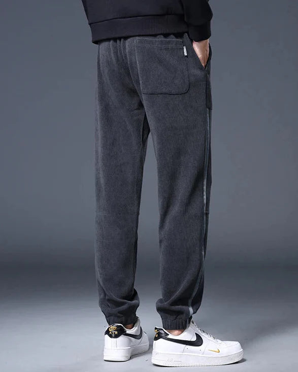Back view of Amos Corduroy Joggers in dark gray, showcases relaxed taper, large pockets, and ankle cuffs.