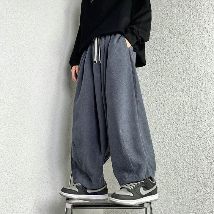 Relaxed corduroy pants with adjustable drawstring and deep pockets, styled casually with sneakers and a black top.