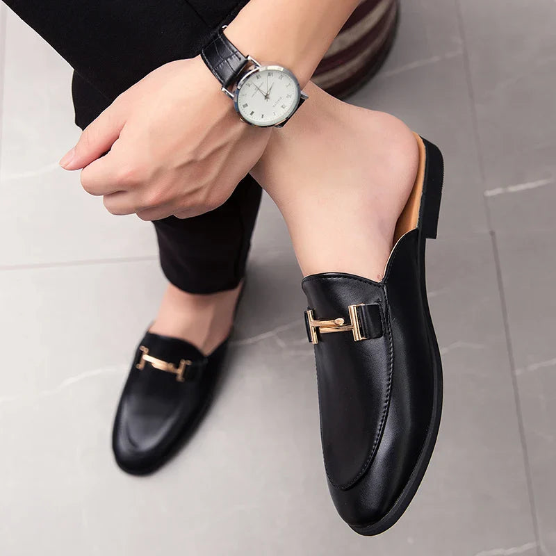 Santino Backless Slide Loafers in black with gold bit detail, styled with a watch, showcasing a sleek and polished look.