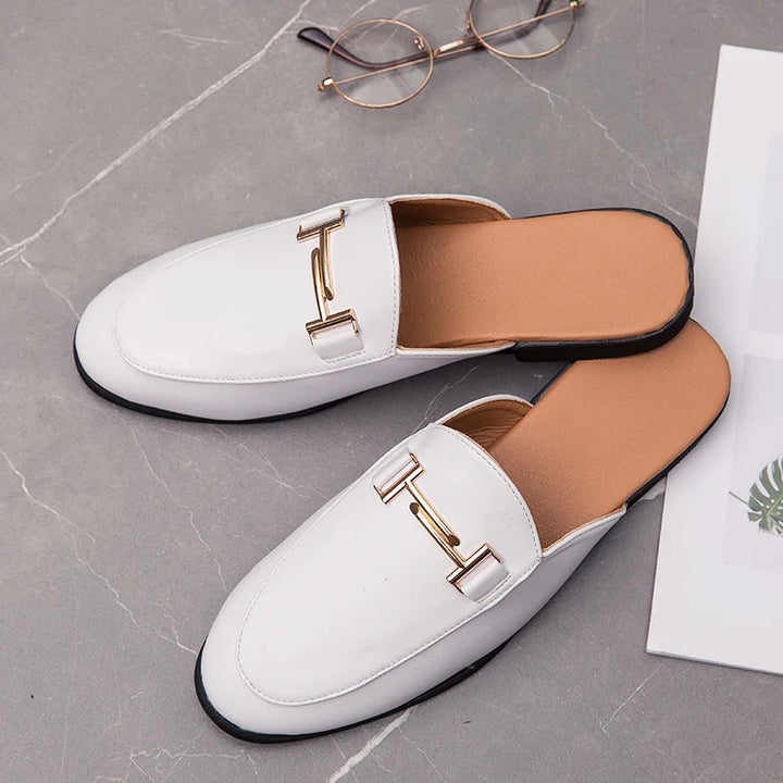 White Santino backless slide loafers with gold bit detail on a gray surface.