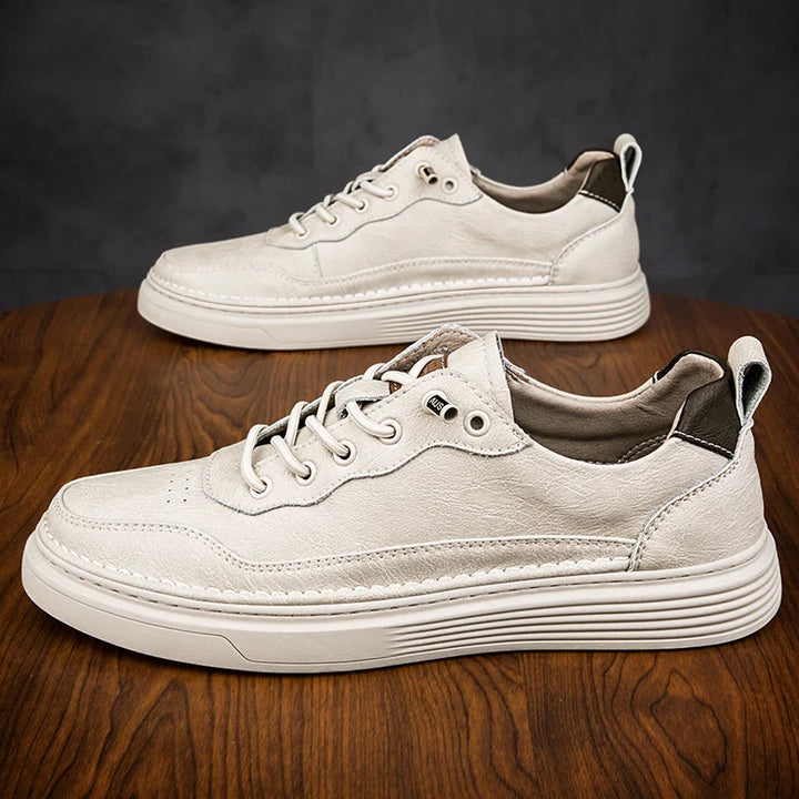 Alvo genuine leather sneakers in white on wooden surface, showcasing artisanal hand-stitched detailing and modern design.