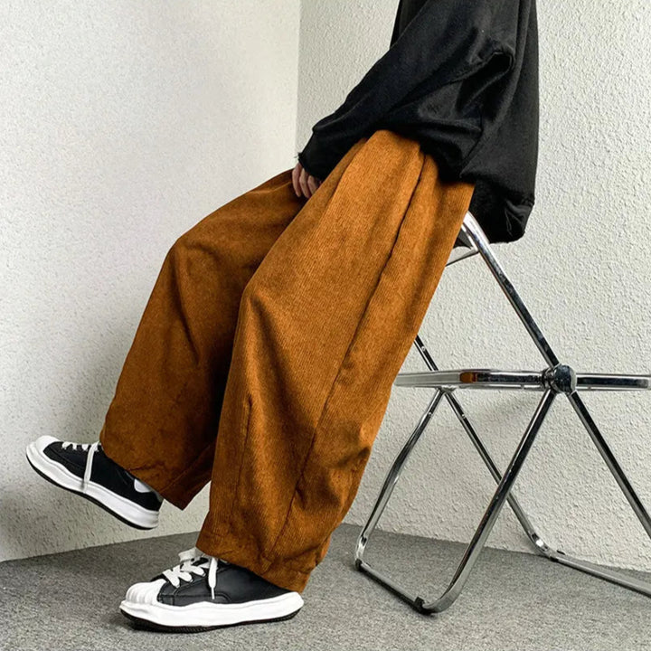 Model wearing Arlo corduroy pants in burnt orange with wide-leg fit, styled with black sneakers.