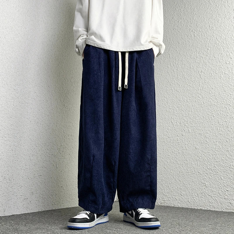 Model wearing Arlo Corduroy Pants with adjustable drawstring waist and wide-leg fit in navy blue.