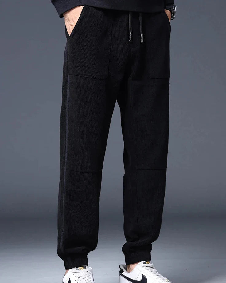 Men's black wide-wale corduroy joggers with relaxed tapered fit, functional pockets, and adjustable drawstring waist.