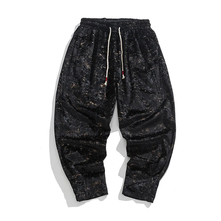 Black crushed velvet joggers with elastic cuffs and drawstring waist, showcasing a relaxed fit and textured finish.