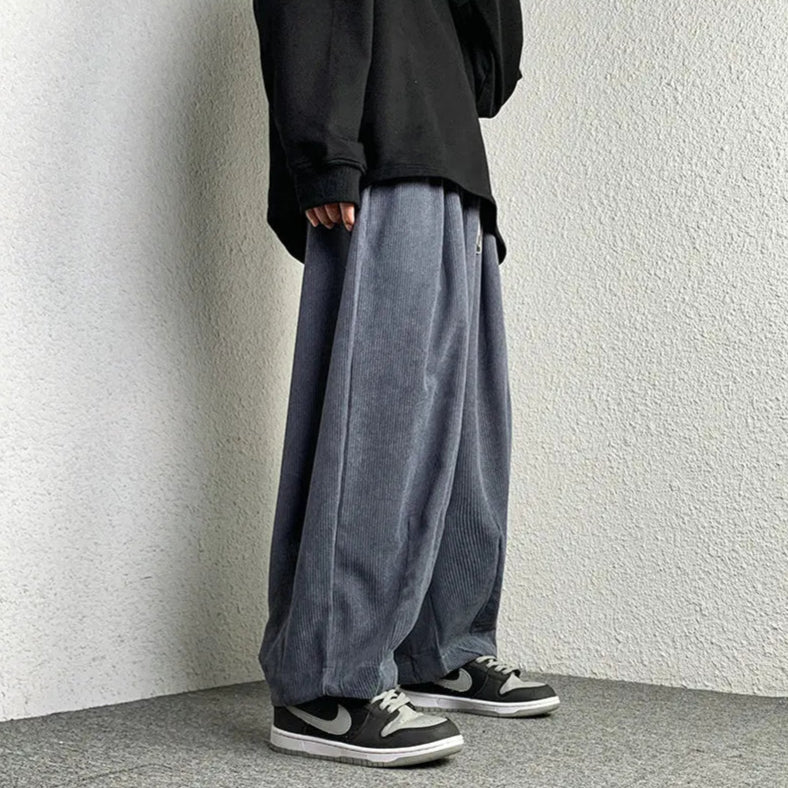 Stylish person wearing Arlo corduroy pants with a wide-leg fit, paired with a black oversized shirt and sneakers.