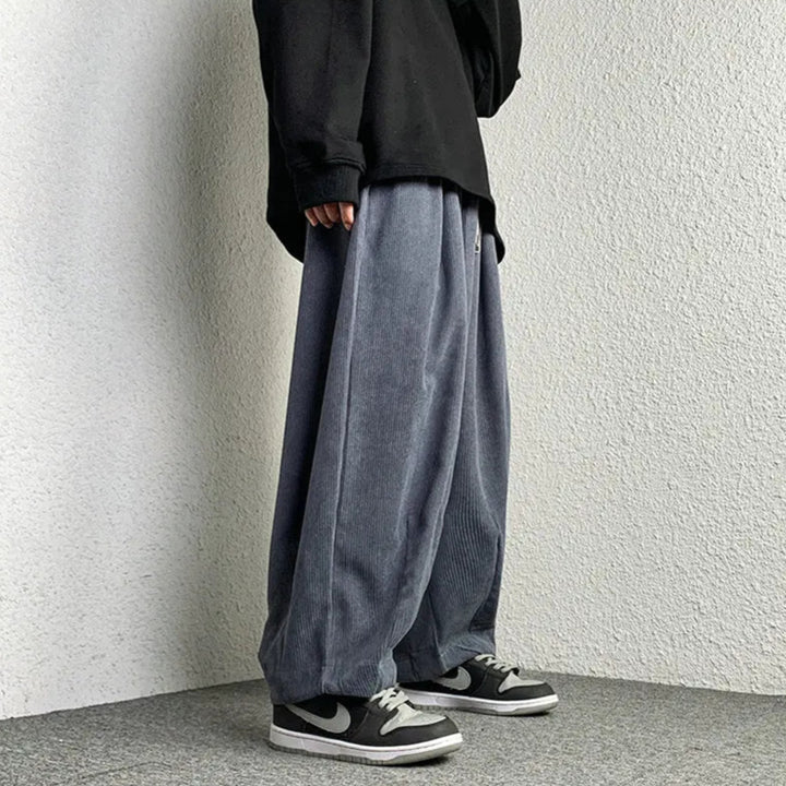 Stylish person wearing Arlo corduroy pants with a wide-leg fit, paired with a black oversized shirt and sneakers.