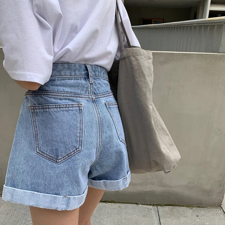 High-waisted Sienna Retro Denim Shorts with cuffed hems, paired with a casual white tee and tote bag.
