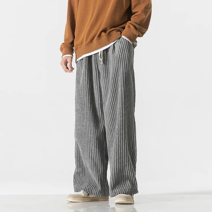 Men's Barron Corduroy Pants in gray with wide-leg fit and elastic waistband, styled with a cozy brown sweater.