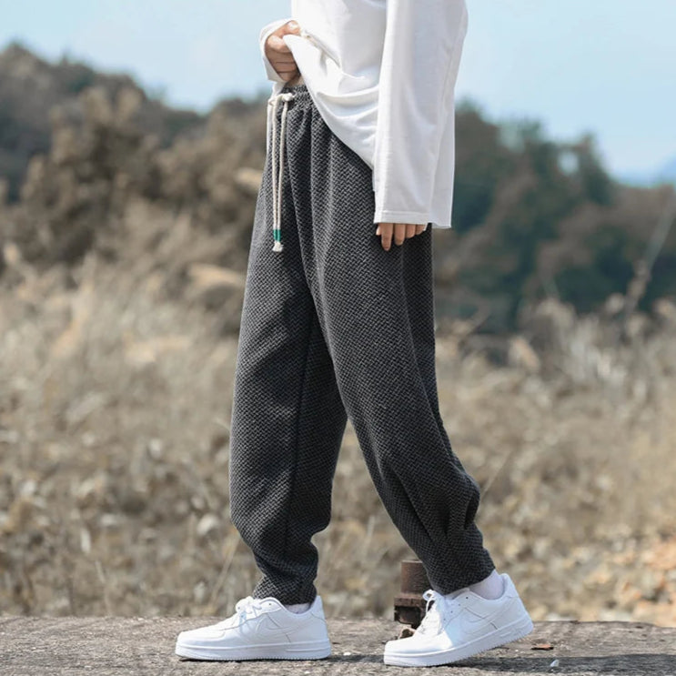Person wearing Oslo Textured Joggers with adjustable drawstring waist and tapered cuffs in a relaxed outdoor setting.