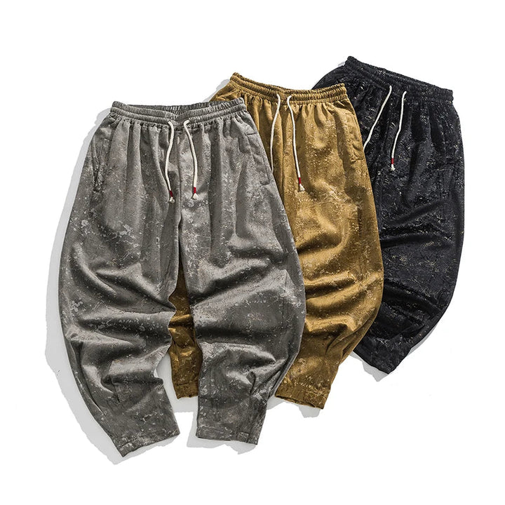 Stylish crushed velvet joggers in gray, gold, and black with elastic cuffs and drawstring waist.
