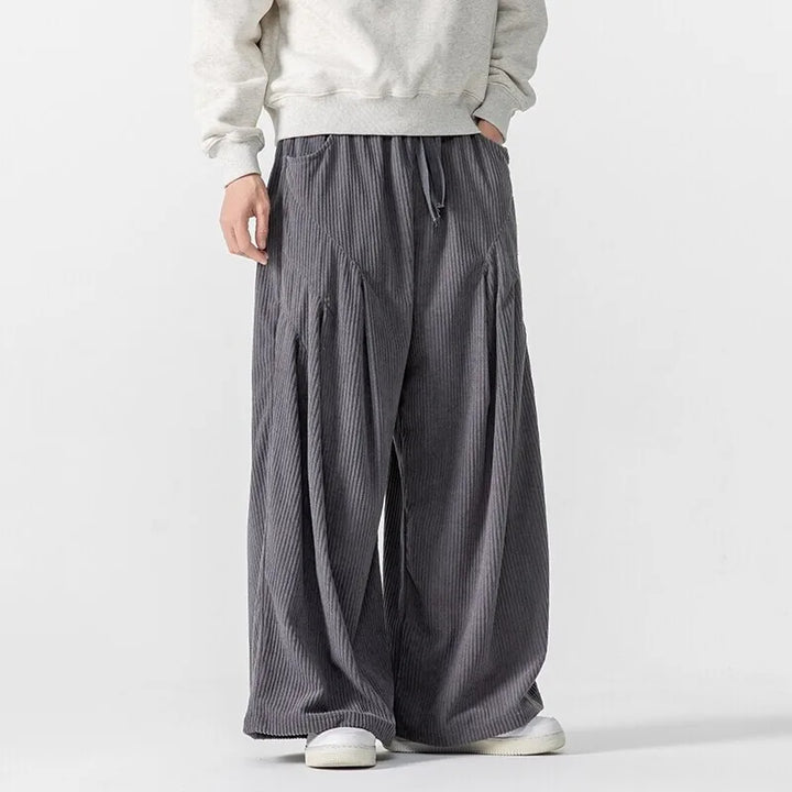 Hollis wide-leg corduroy pants with deep pleats and elastic waistband, styled for a bold, structured look.