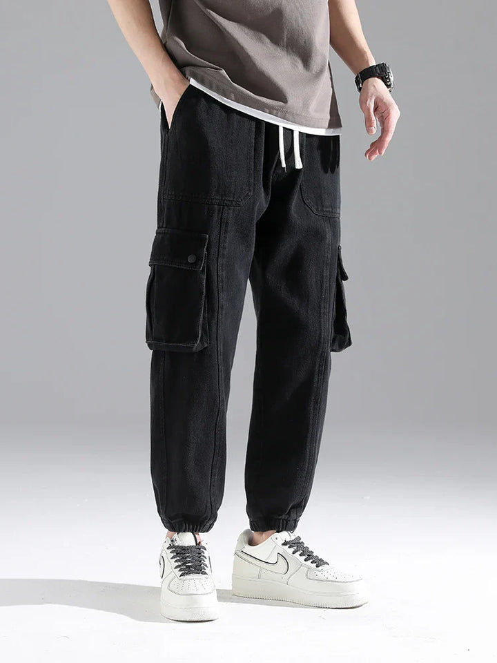 Lennox Cargo Joggers in black, heavyweight cotton blend, featuring oversized snap pockets and elastic ankle cuffs.