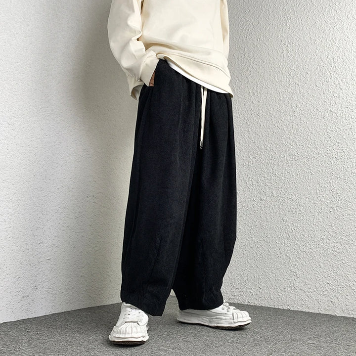 Model wearing Arlo Corduroy Pants with wide-leg fit and adjustable drawstring waist, styled casually with white shoes.