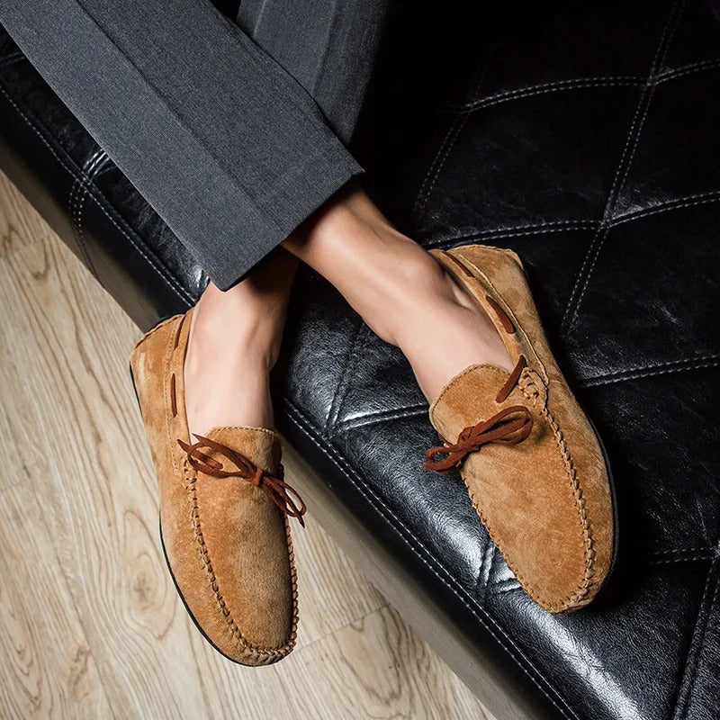 Monte Carlo genuine suede loafers showcasing hand-stitched craftsmanship and premium leather laces, worn in a stylish setting.