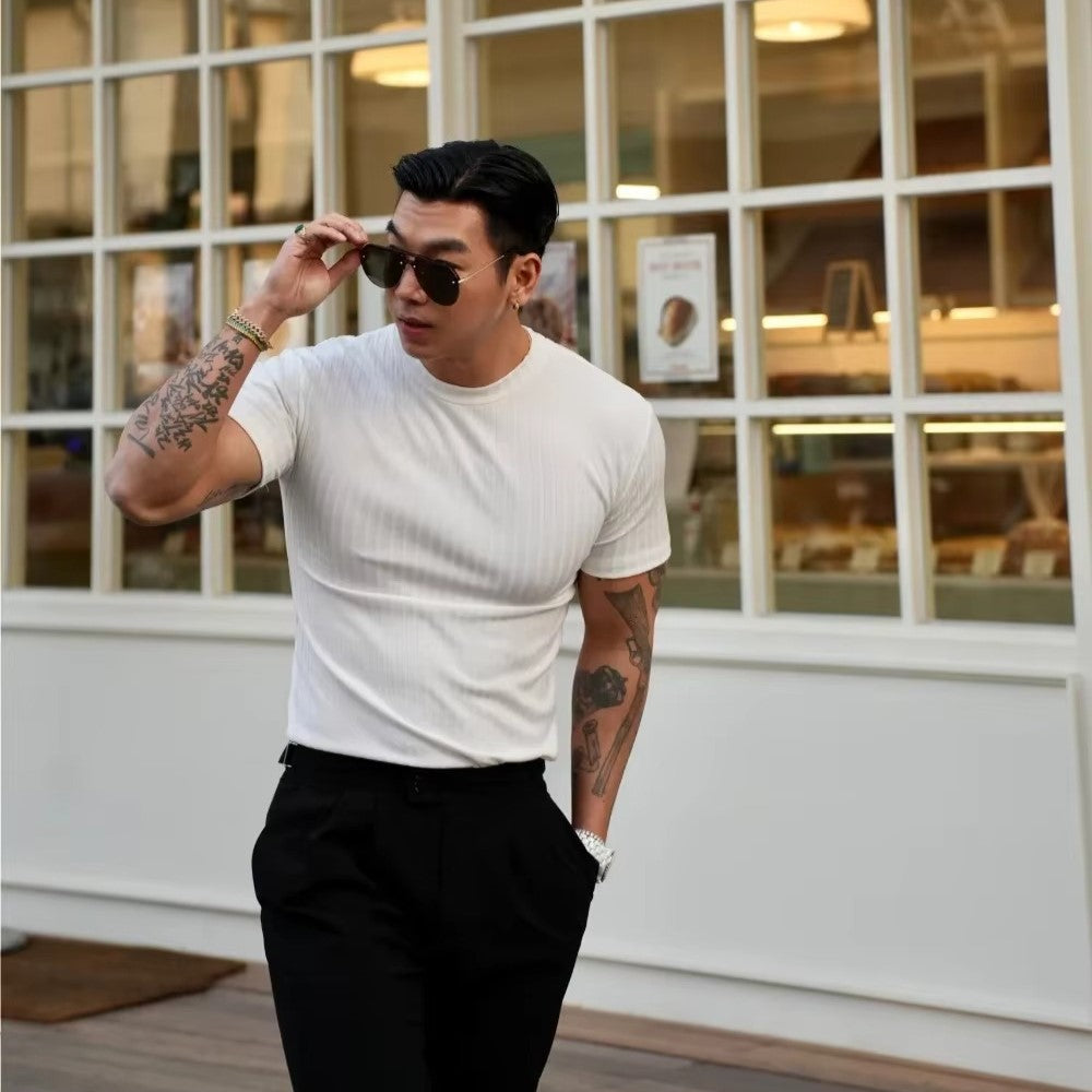 Man wearing a white ribbed knit shirt and sunglasses, showcasing a tailored fit and refined texture.