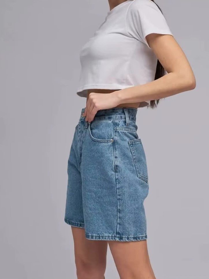 Side view of a model wearing Lyra vintage high-waisted denim shorts with a cropped white top, showcasing a classic fit.