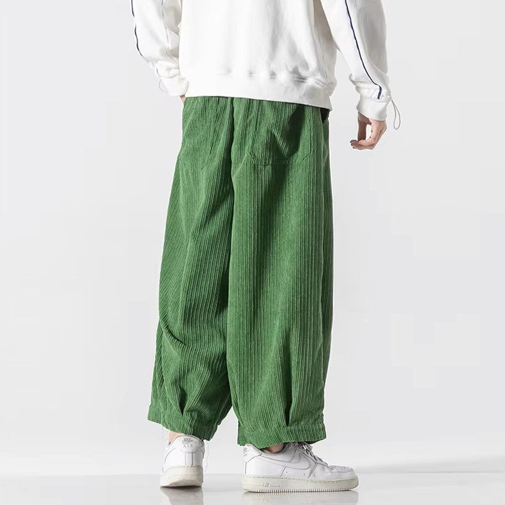 Oversized green corduroy pants with deep pleats and an elastic waistband, showcasing a relaxed fit and effortless style.