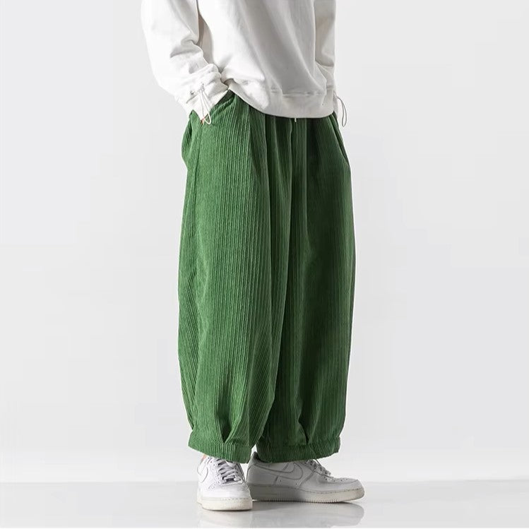 Oversized green corduroy pants with deep pleats and elastic waistband for a relaxed fit and effortless movement.